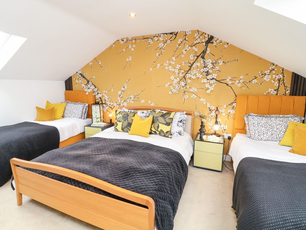 A bedroom with two beds and a floral wall design at Hayloft in Scampton