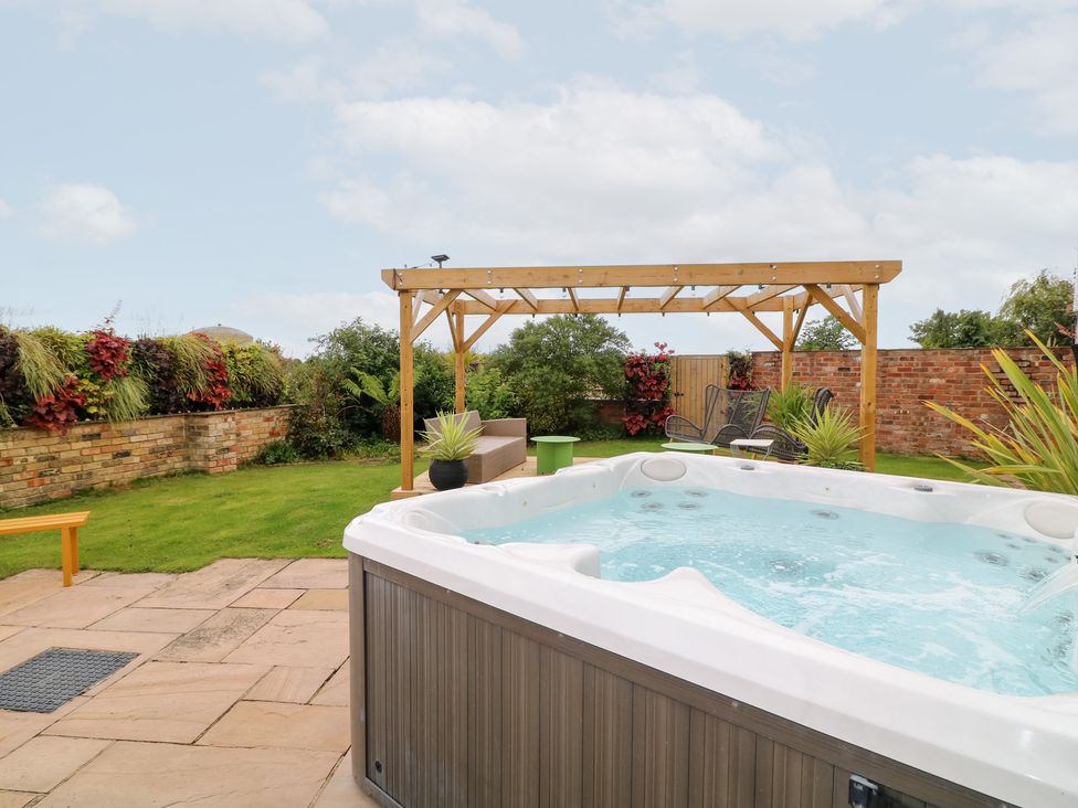 A garden with a hot tub and pergola at Hayloft in Scampton