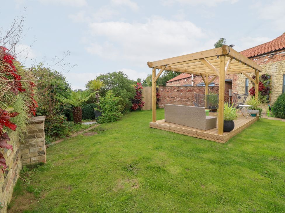 A garden with a patio and plants at Hayloft in Scampton