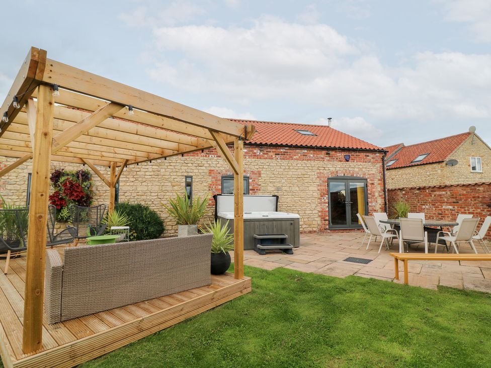 A garden with a patio and seating area at Hayloft in Scampton