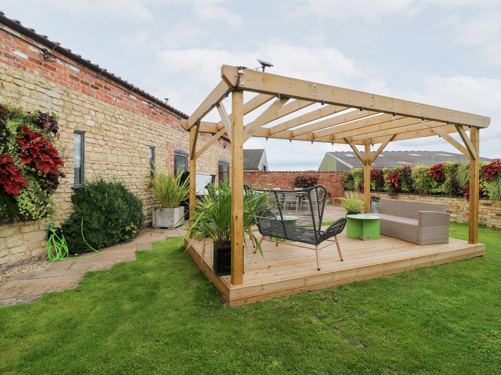 A garden with a pergola and seating area at Hayloft in Scampton