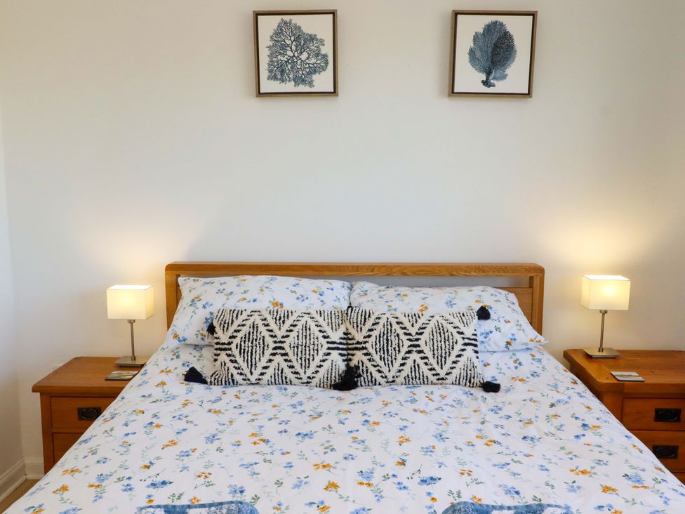 A bed with floral sheets and decorative pillows at 6 Westview in Embleton