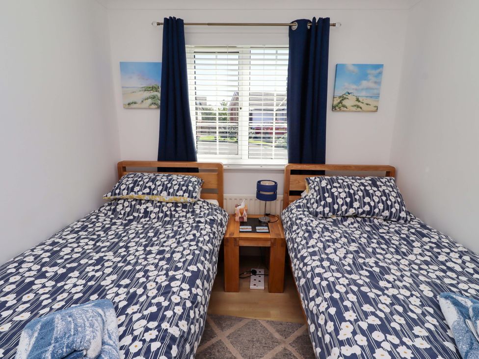 A bedroom with two beds and a bedside table at 6 Westview Embleton