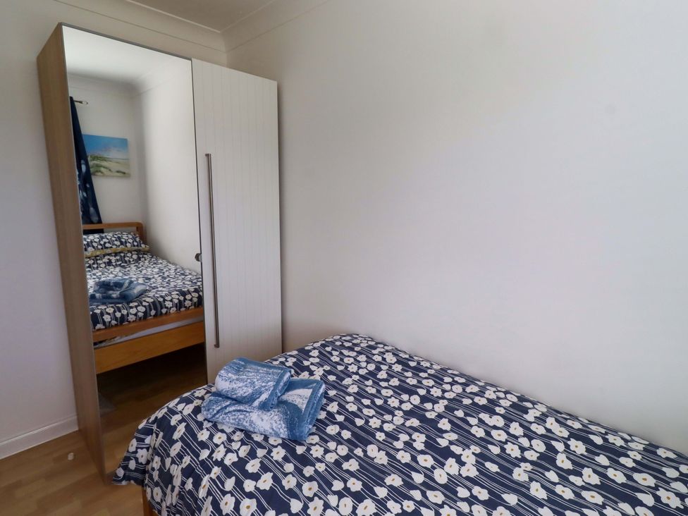 A bedroom with two beds and a wardrobe at 6 Westview Embleton