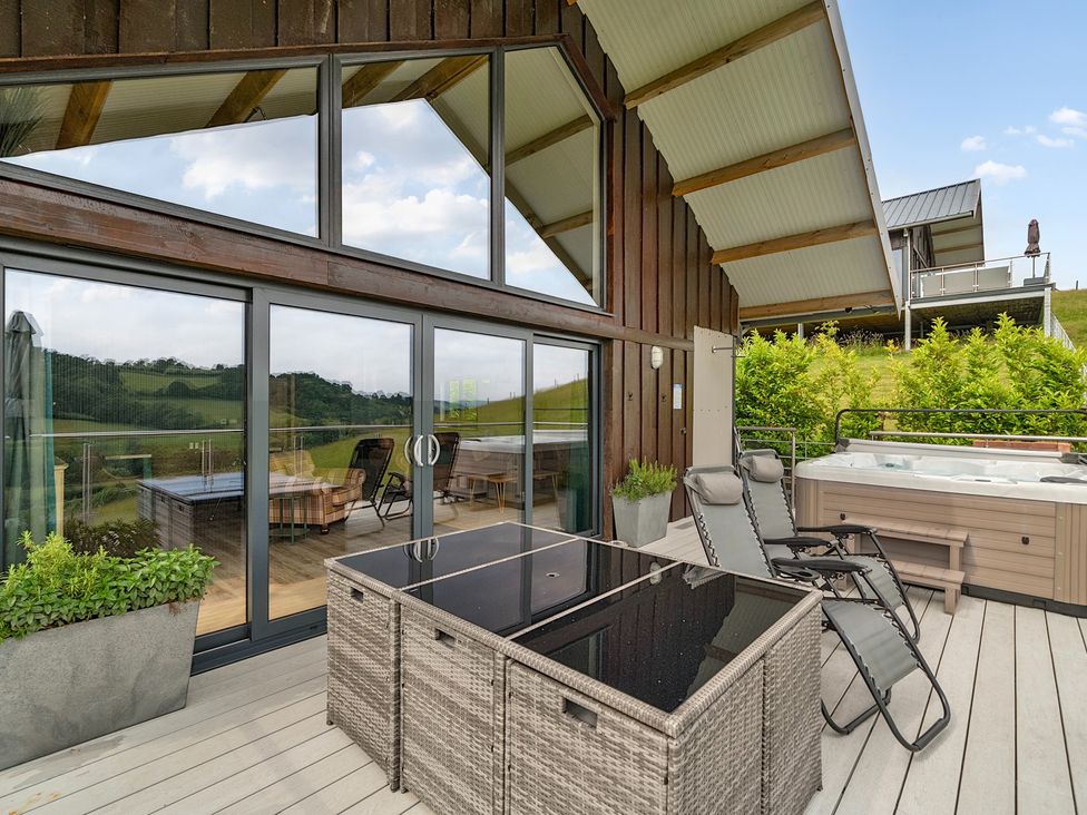 An outdoor area with hot tub and furniture at Bwncath in Garthmyl