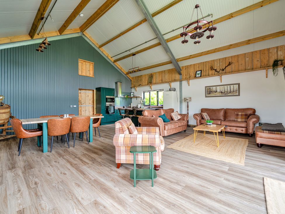 A living room with furniture and kitchen area at Bwncath Garthmyl