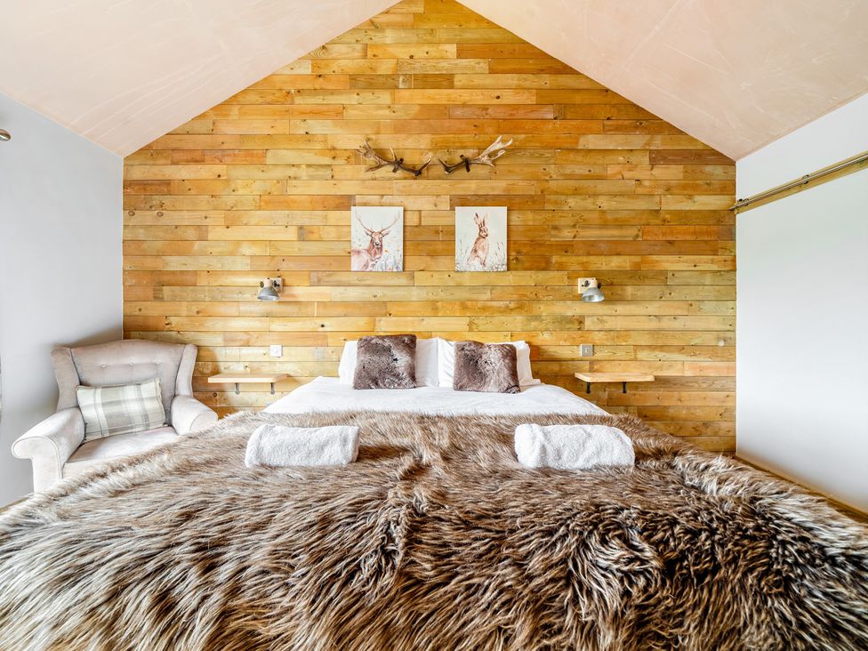 A bedroom with a bed and armchair at Bwncath in Garthmyl