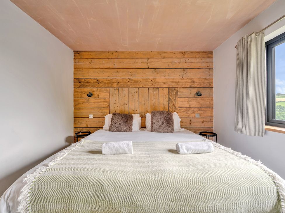 A bedroom with a bed and wooden wall at Bwncath Garthmyl