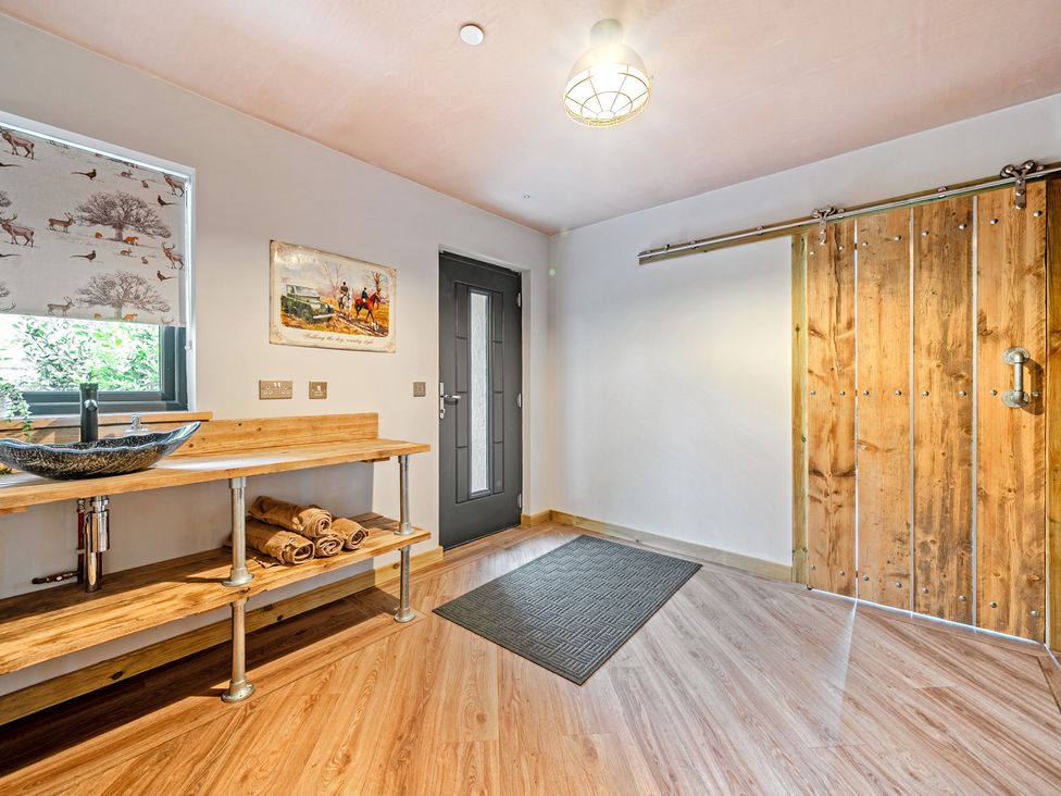 An entrance with a sink and wooden shelf at Bwncath in Garthmyl