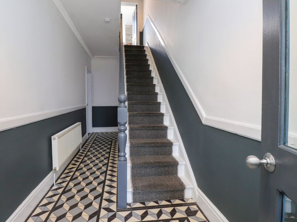 A hallway with a staircase and patterned flooring at Ty Haul in Rhosneigr