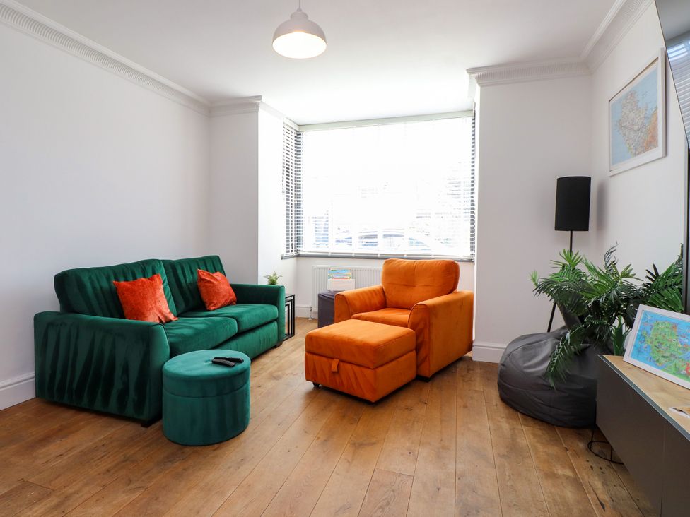 A living room with a green sofa and an orange armchair at Ty Haul in Rhosneigr