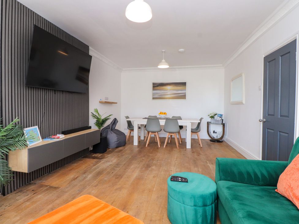 A living room with a television and dining table at Ty Haul in Rhosneigr