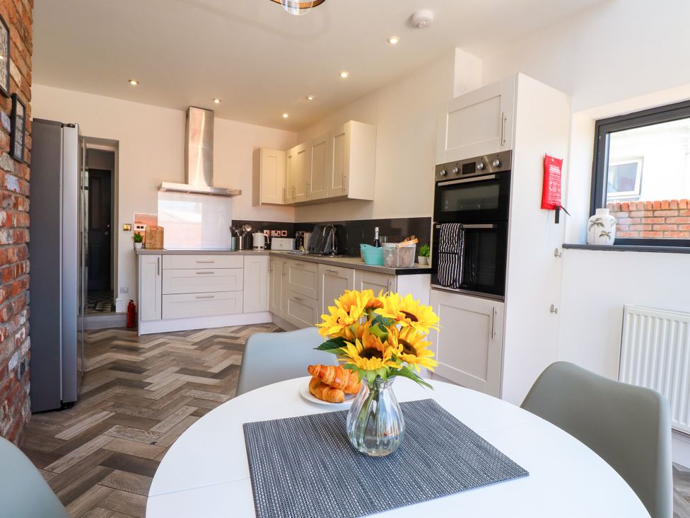 A kitchen with a round table and flowers at Ty Haul Rhosneigr