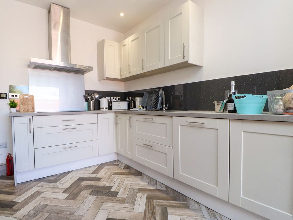 A kitchen with cabinets and appliances at Ty Haul in Rhosneigr