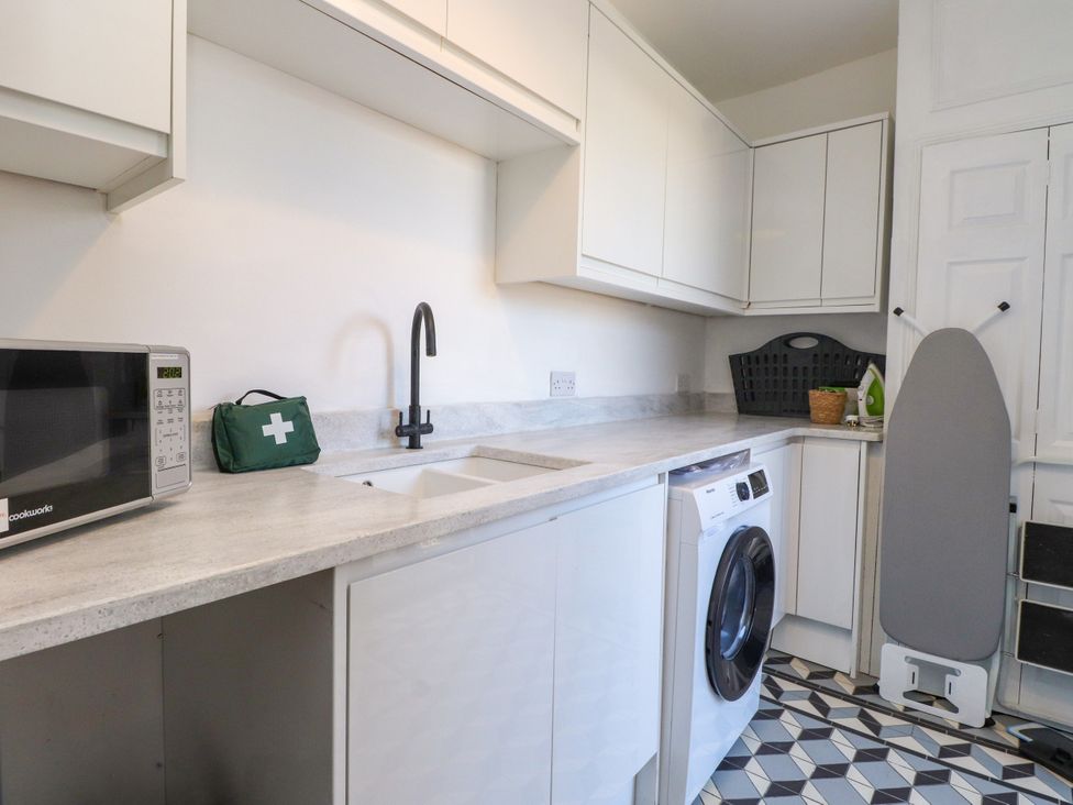 A laundry room with a washing machine and a microwave at Ty Haul in Rhosneigr