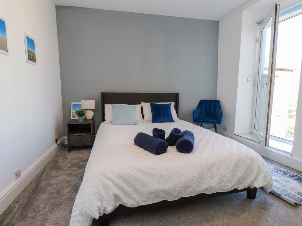 A bedroom with a bed and towels at Ty Haul in Rhosneigr
