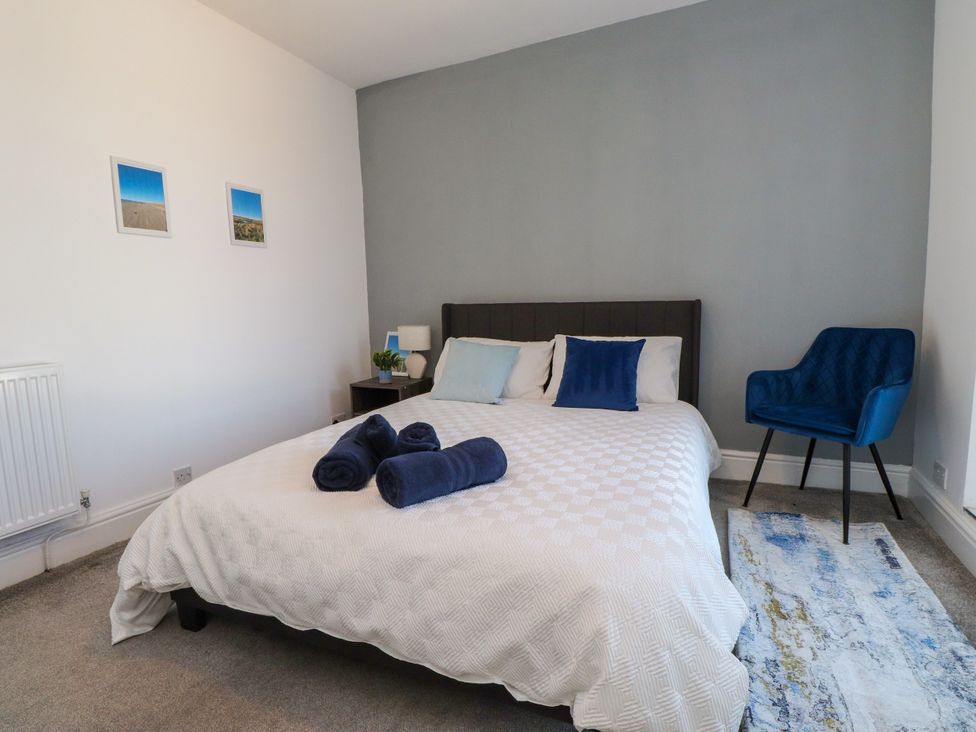 A bedroom with a bed and a blue chair at Ty Haul in Rhosneigr