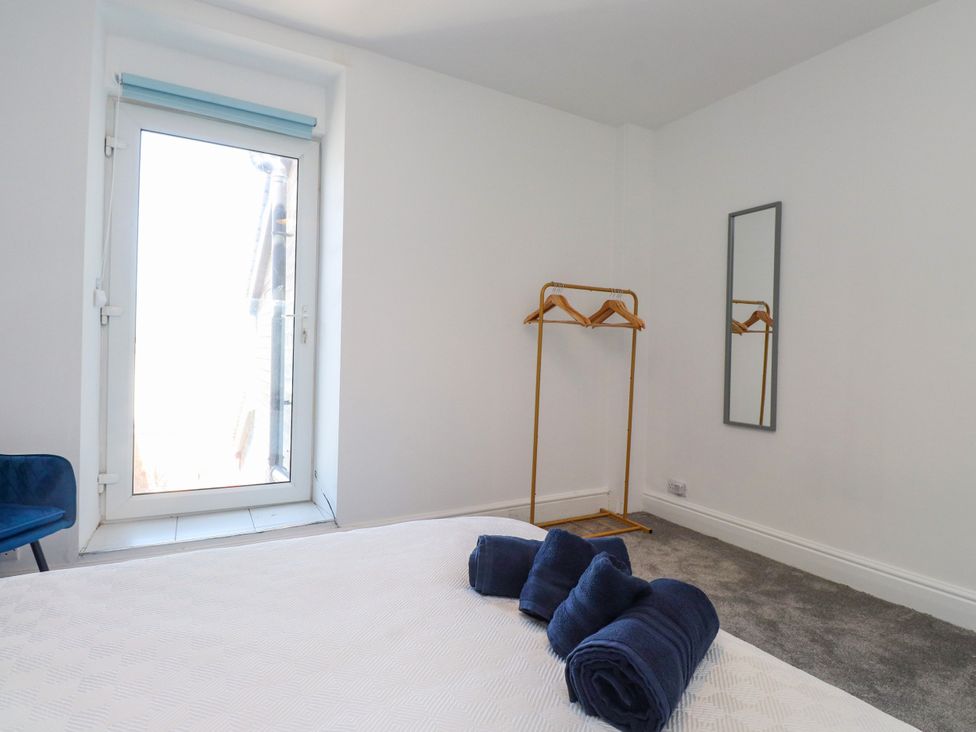 A bedroom with a door, hangers, towels, and a mirror at Ty Haul in Rhosneigr