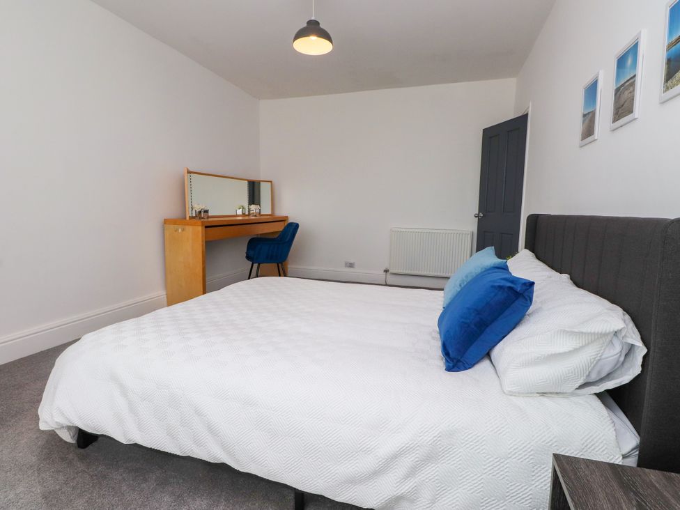 A bedroom with a bed and a desk at Ty Haul in Rhosneigr