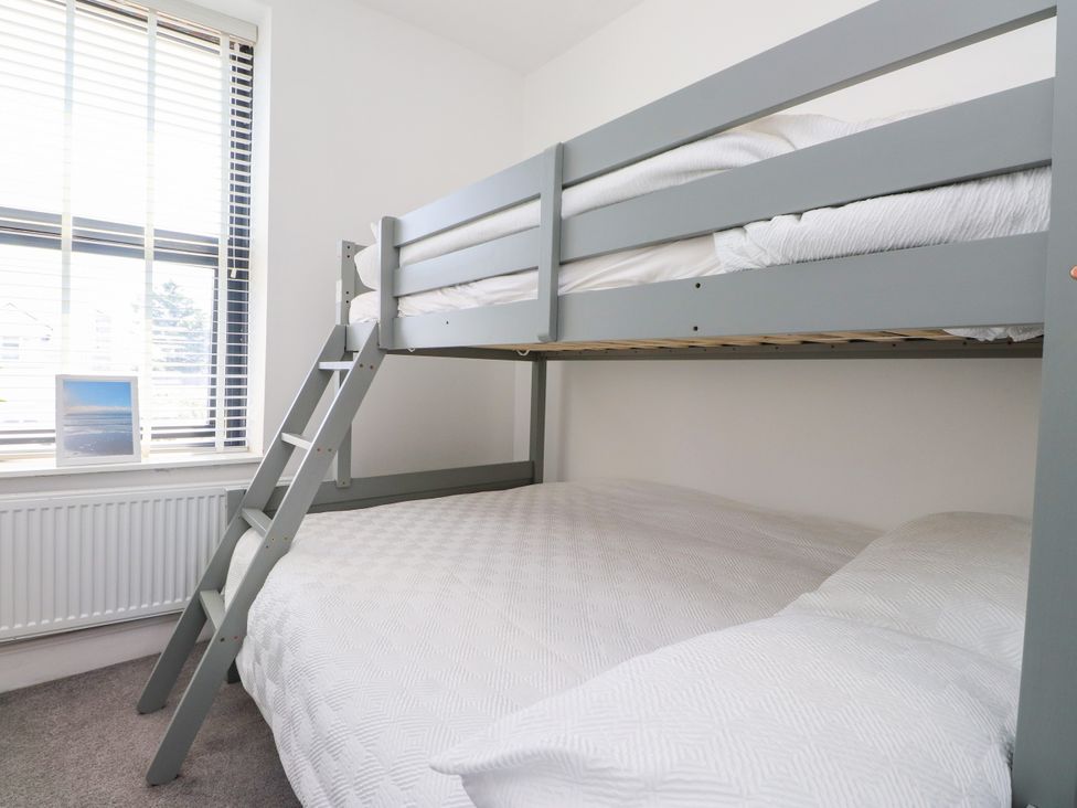 A bedroom with a bunk bed and a window at Ty Haul in Rhosneigr
