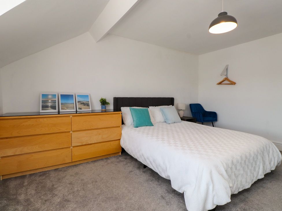 A bedroom with a bed and dresser at Ty Haul in Rhosneigr