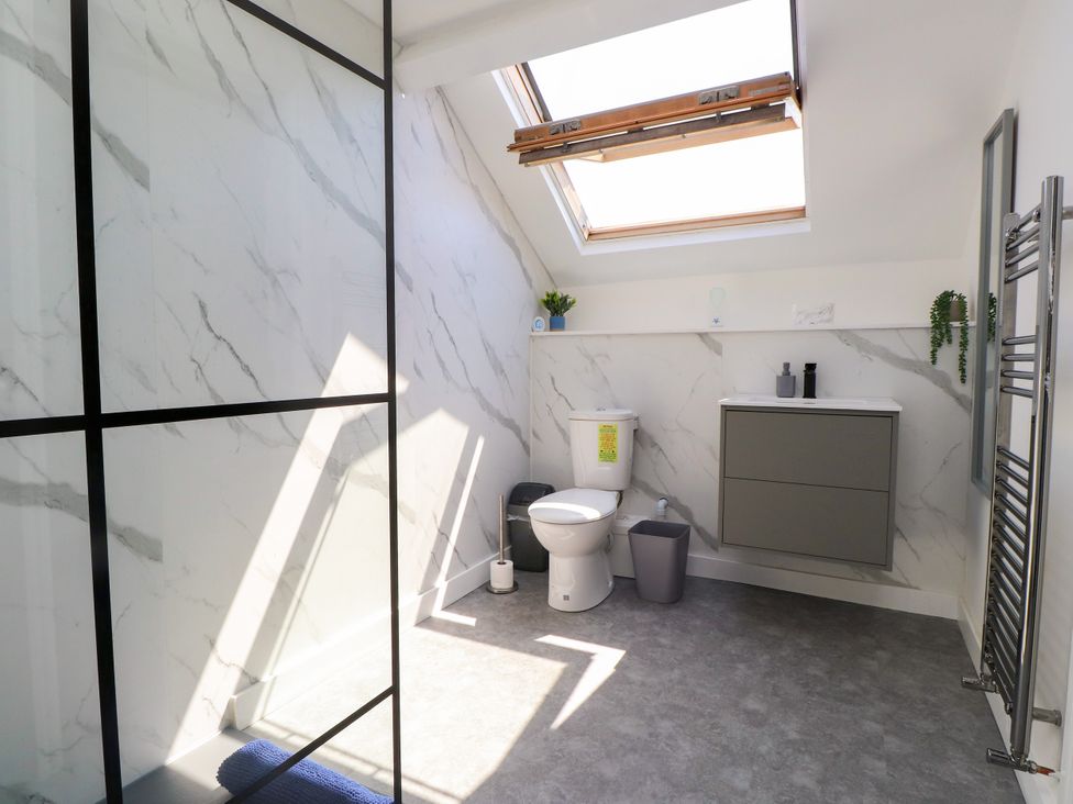 A bathroom with a shower, toilet, sink and skylight at Ty Haul in Rhosneigr
