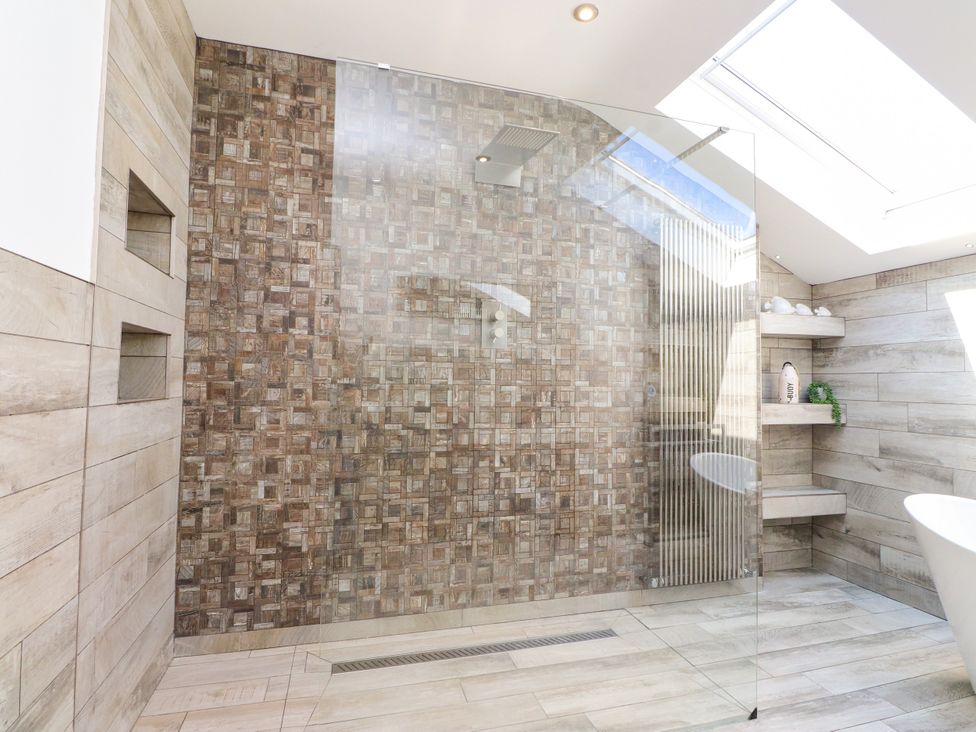A bathroom with a shower and bathtub at Ty Haul in Rhosneigr