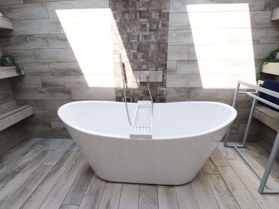 A bathroom featuring a bathtub and wall tiles at Ty Haul in Rhosneigr