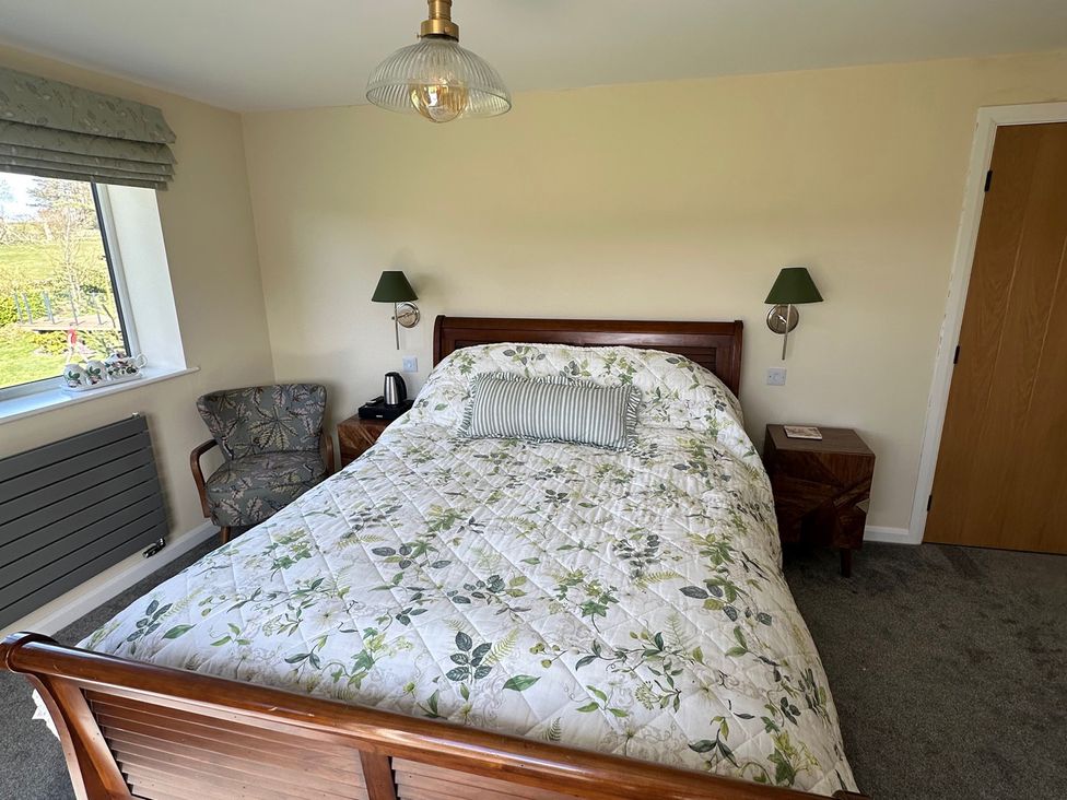 A bedroom with a bed and armchair at How Hill Farm Cottage in Greystoke