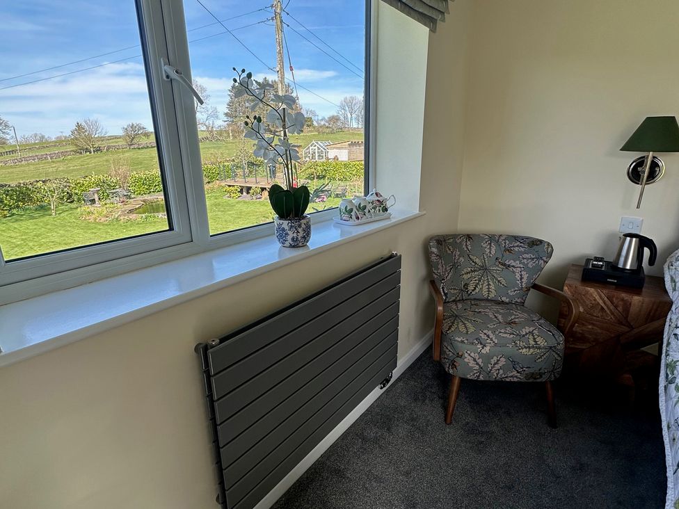 A bedroom with a chair and lamp at How Hill Farm Cottage in Greystoke