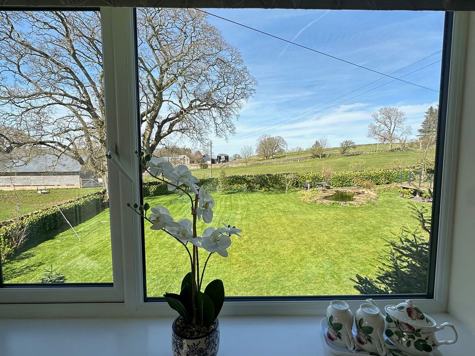 A window view overlooking a garden with a pond at How Hill Farm Cottage in Greystoke