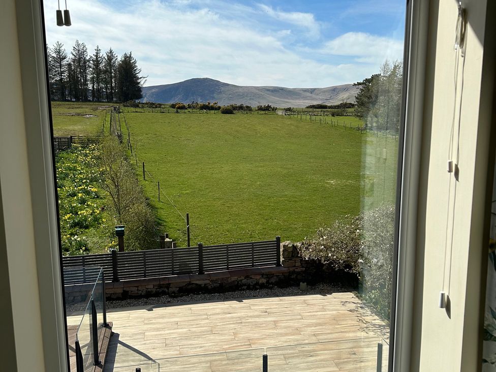 View of grass field and mountains from a window at How Hill Farm Cottage in Greystoke