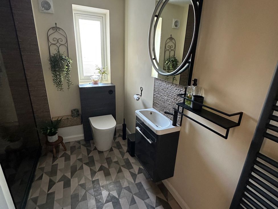 A bathroom with a sink, toilet, and mirror at How Hill Farm Cottage in Greystoke