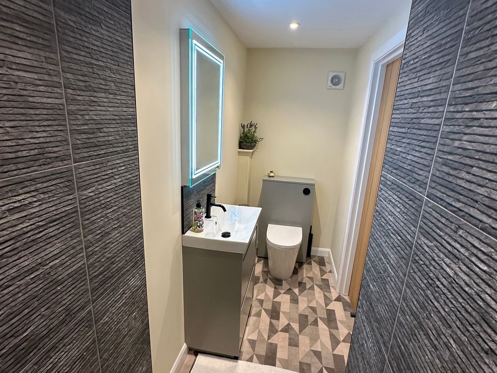 A bathroom with a sink, toilet and mirror at How Hill Farm Cottage in Greystoke