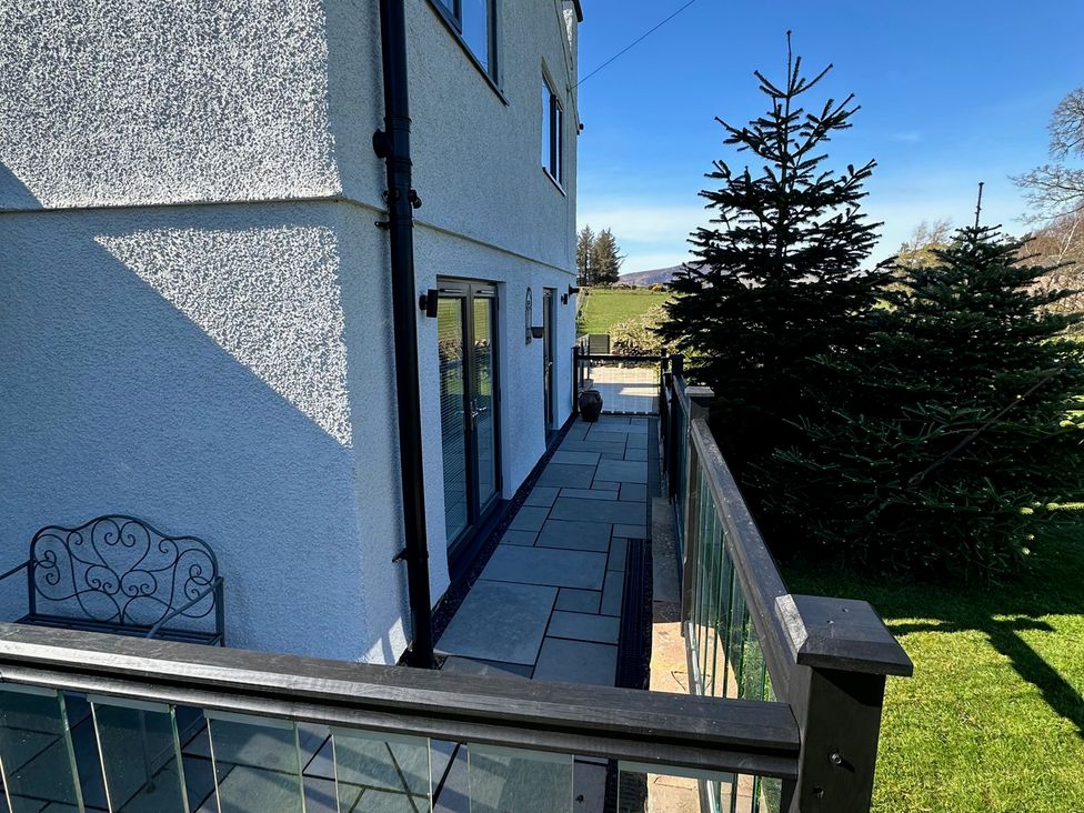 An outdoor area with a patio and glass doors at How Hill Farm Cottage in Greystoke
