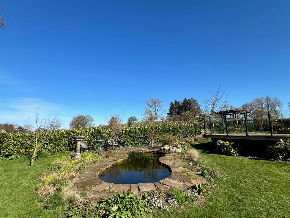 A garden with a pond and flower bed at How Hill Farm Cottage in Greystoke