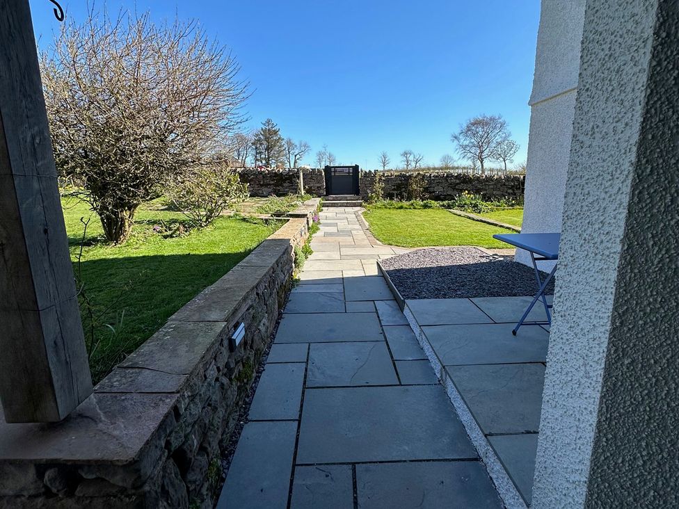 A garden view with a pathway, stone wall, and gate at How Hill Farm Cottage in Greystoke