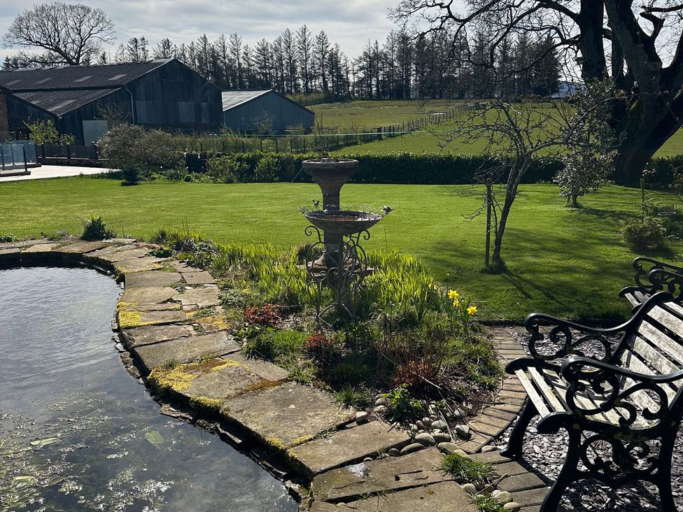 A garden with a pond and fountain at How Hill Farm Cottage Greystoke