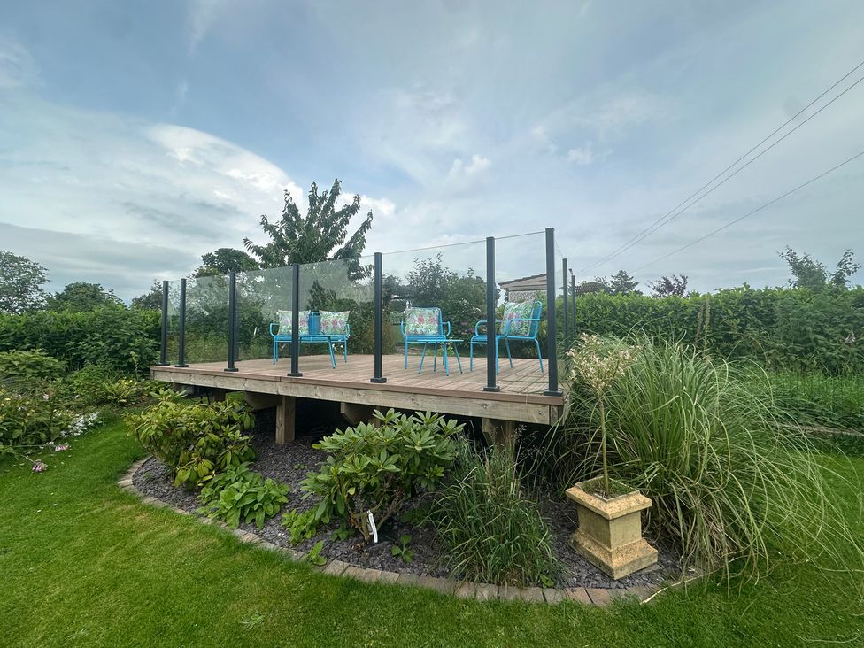 A garden deck with chairs and plants at How Hill Farm Cottage Greystoke