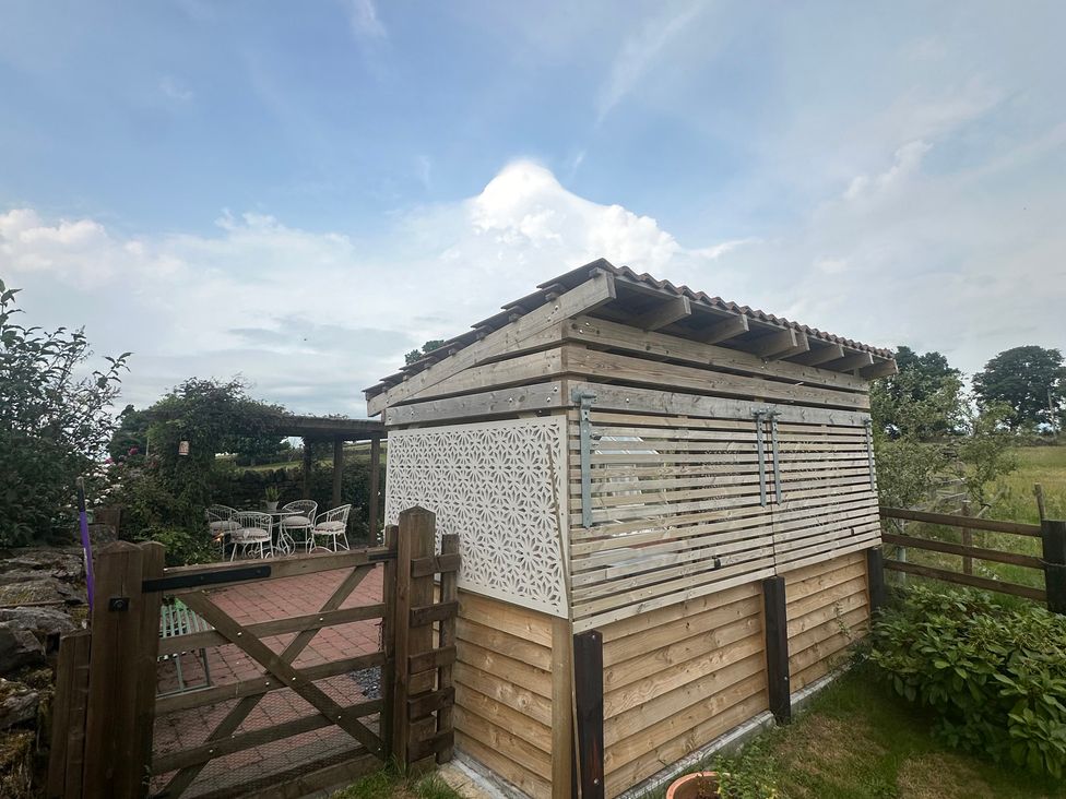 A wooden shed with decorative panels in a garden at How Hill Farm Cottage Greystoke