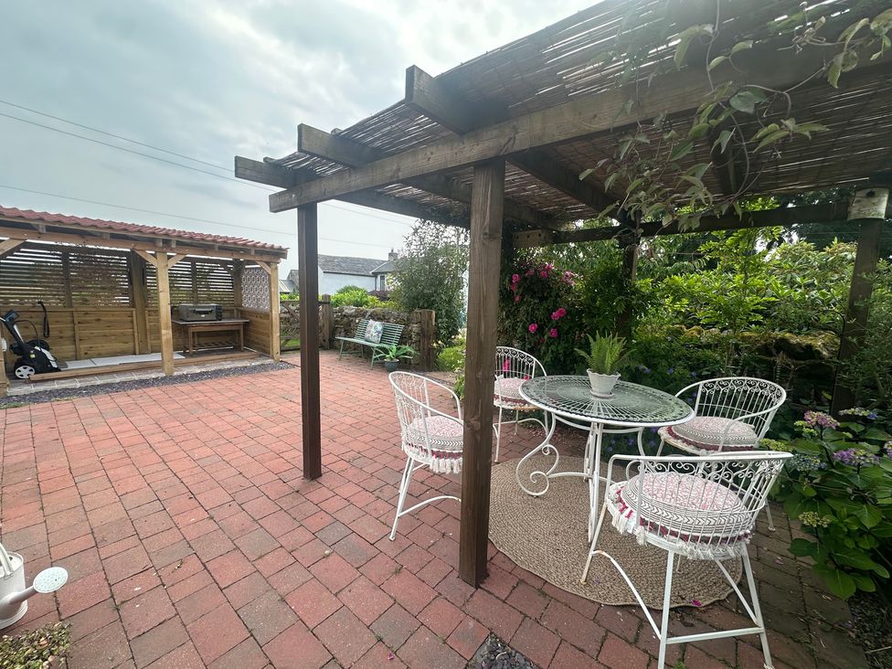 A garden with a table and chairs under a pergola at How Hill Farm Cottage in Greystoke