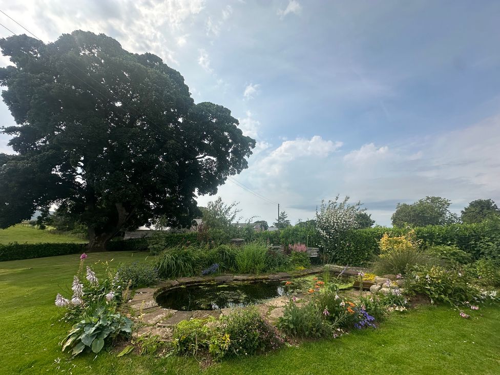 A garden with a pond and flowers at How Hill Farm Cottage Greystoke
