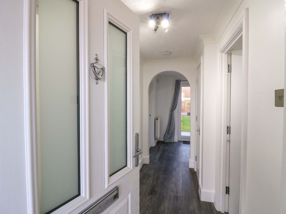 A hallway with a door and a view of a garden at 79 Selsey Avenue