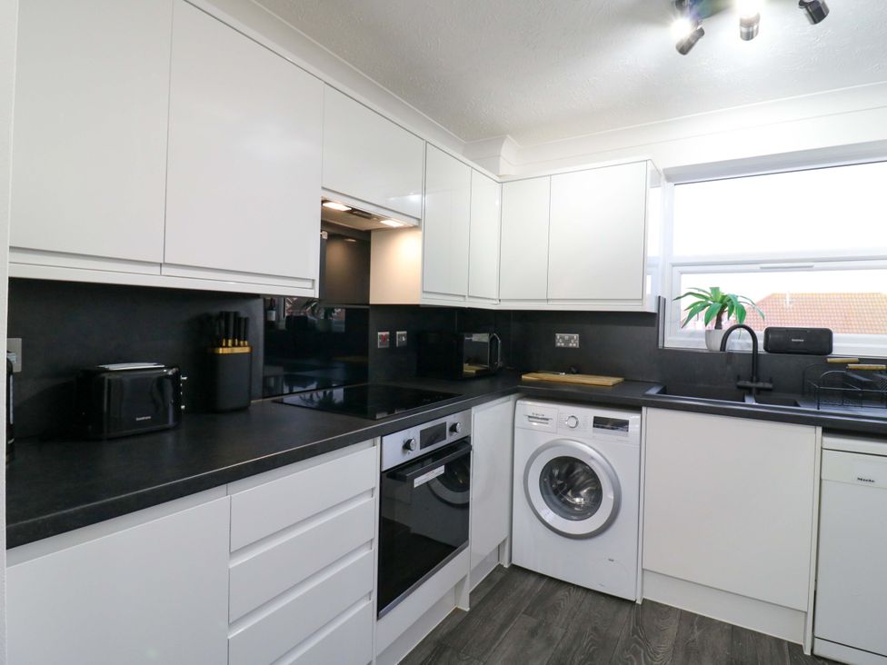 A kitchen with cabinets, washing machine, and oven at 79 Selsey Avenue