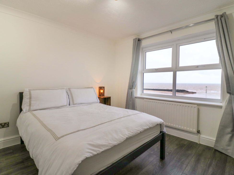 A bedroom with a bed and window overlooking the sea at 79 Selsey Avenue