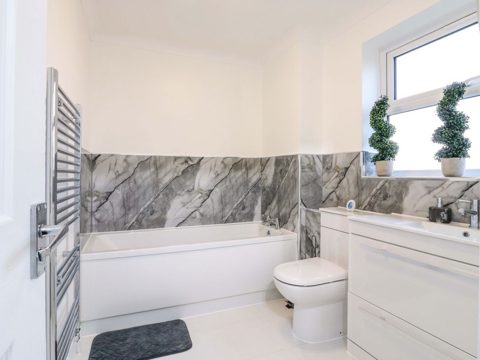 A bathroom with a bathtub, toilet, sink, and towel radiator at 79 Selsey Avenue 