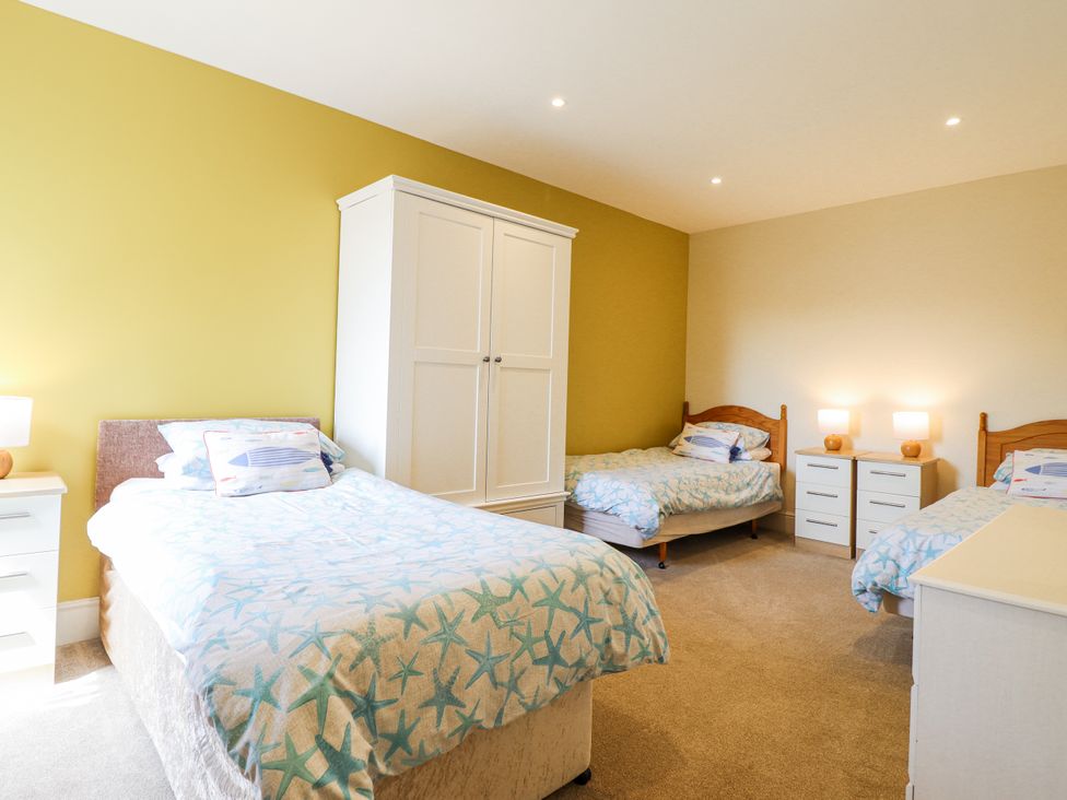 A bedroom with three beds and a wardrobe at Bryn Mor in Benllech