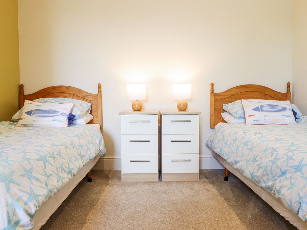 A bedroom with two single beds and nightstands at Bryn Mor in Benllech