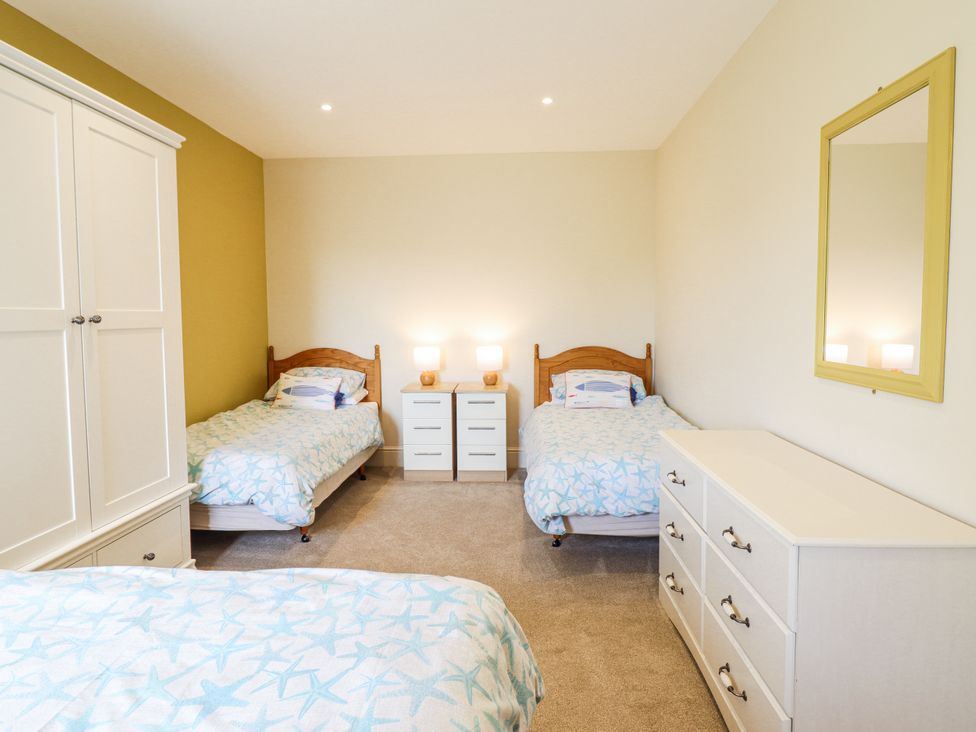 A bedroom with two beds and a wardrobe at Bryn Mor in Benllech