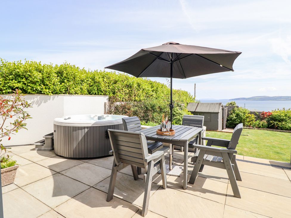 An outdoor seating area with a hot tub and dining table at Bryn Mor in Benllech
